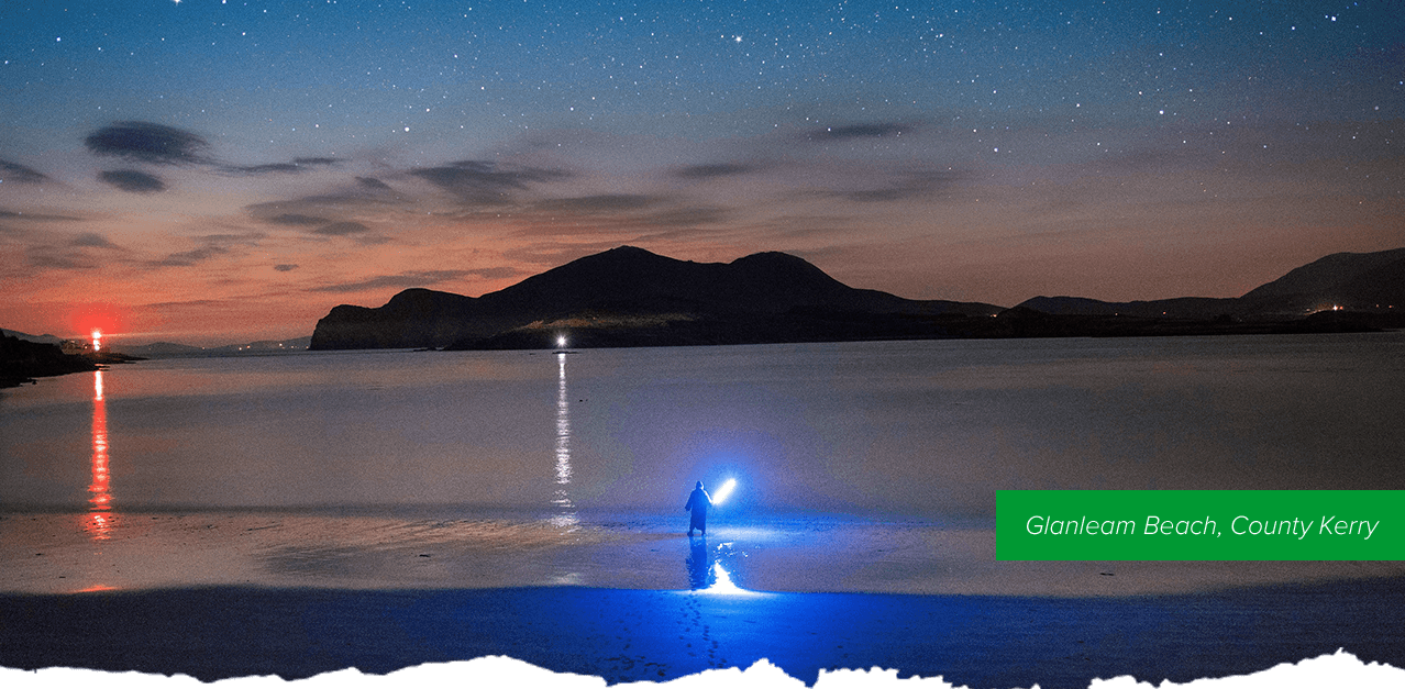 Glanleam Beach, County Kerry - A person with a blue lightsaber standing in the water of Glanleam beach.