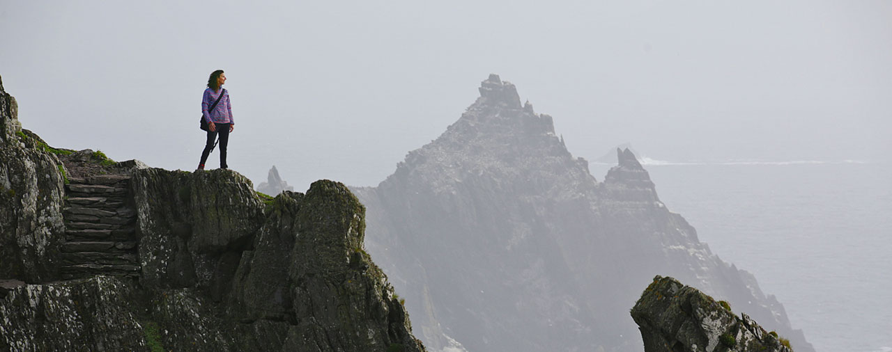 Skellig Michael, County Kerry - A woman standing on a cliff overlooking the ocean. 